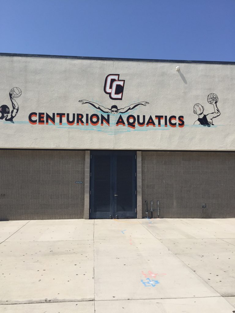 Exterior wall sign reading Centurion Aquatics with a swimmer graphic and school logo on a building wall.