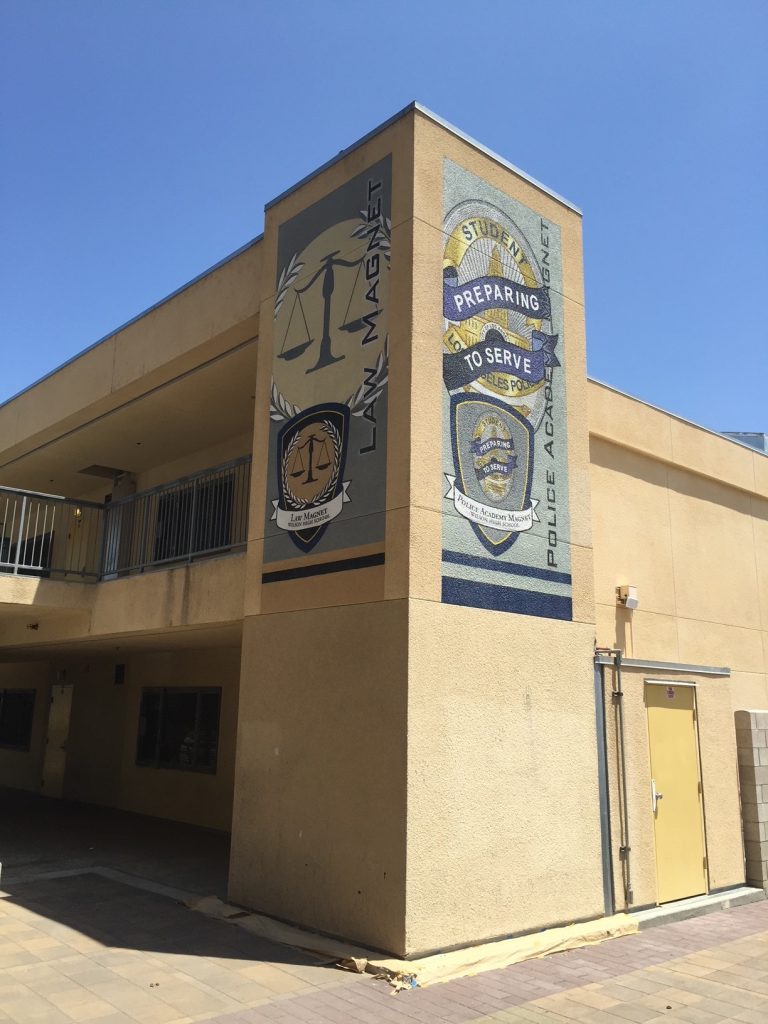 Large exterior wall murals at Wilson High School featuring Police Academy and Law Magnet emblems.